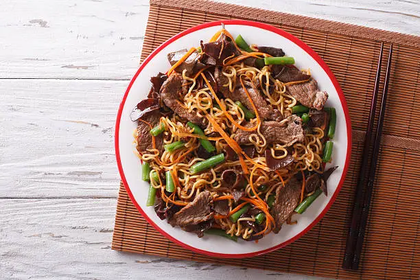 Chinese noodles with beef, muer and vegetables close-up on a plate. horizontal view from above