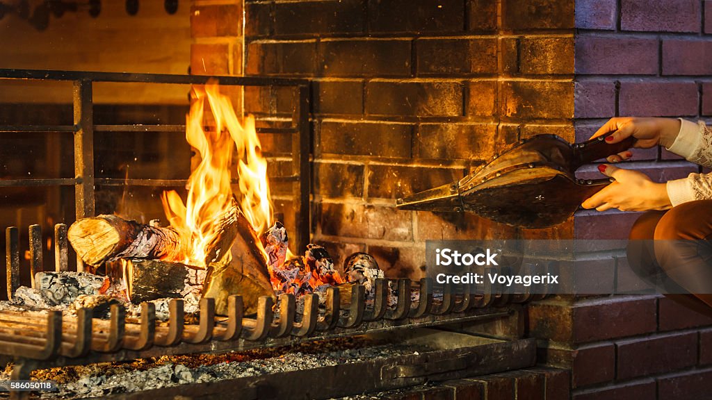 Closeup hands fireplace making fire with bellows. Closeup of human hands at fireplace making fire with bellows. Person heating warming up and relaxing. Winter at home. Bellows Stock Photo