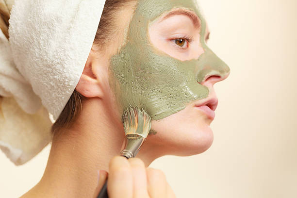 mulher aplicando a máscara de lama com escova de argila para o rosto - face mask imagens e fotografias de stock