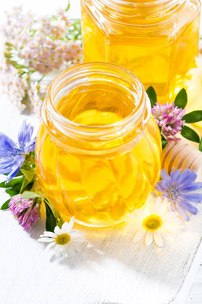 istock jars with fresh flower honey on white wooden board, vertical 586053734