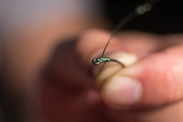 istock Man hand tying a fishing hook. Tie the rig. 586053760