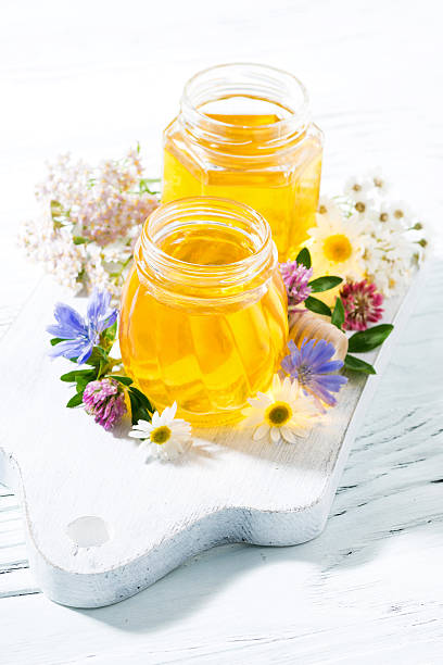istock jars with fresh flower honey on white board, vertical 586053796
