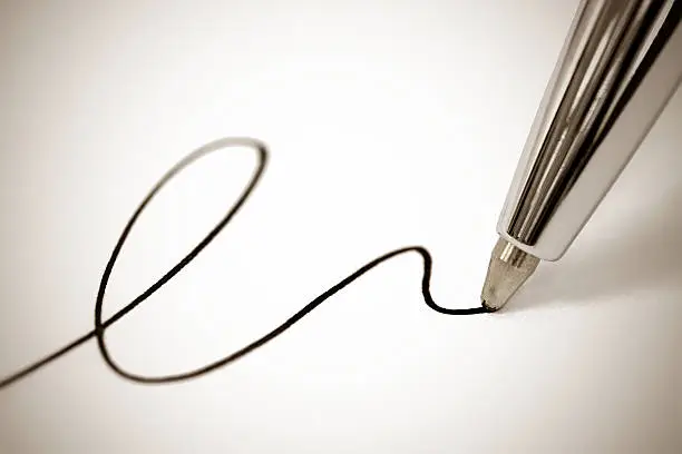Macro picture of a ballpoint pen writing a signature on paper, sepia toned