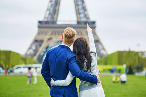 Happy couple looking at the Eiffel tower. Tourists enjoying their vacation in France. Romantic date or traveling couple concept
