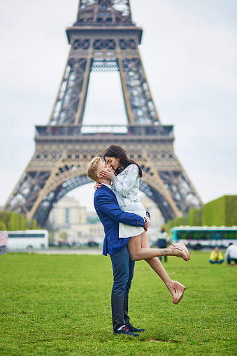 Happy couple near the Eiffel tower. Tourists enjoying their vacation in France. Romantic date or traveling couple concept
