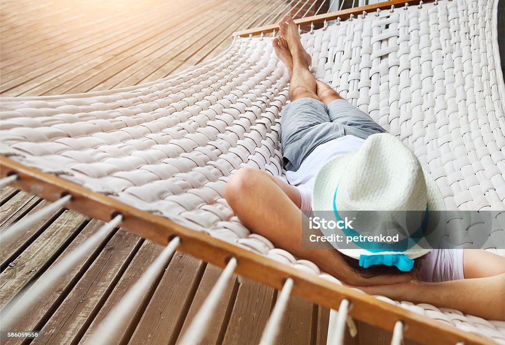 Man in a hammock on summer day Lazy time. Man in hat in a hammock on a summer day Hammock Stock Photo