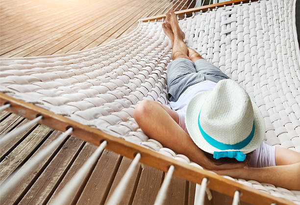 Man in a hammock on summer day Lazy time. Man in hat in a hammock on a summer day hammock stock pictures, royalty-free photos & images