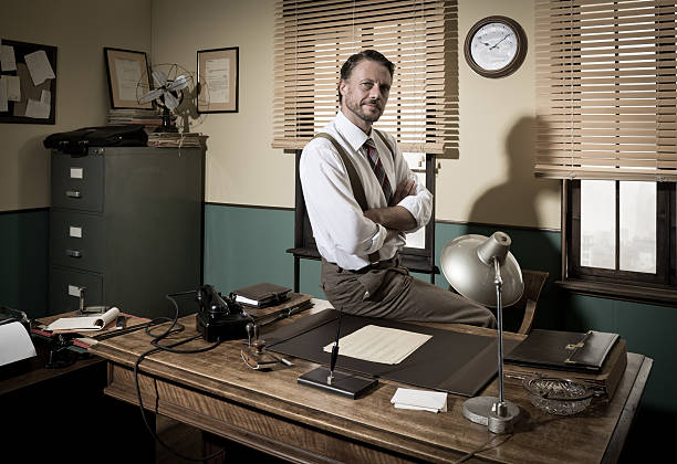 istock Smiling vintage businessman sitting on desk 586060870