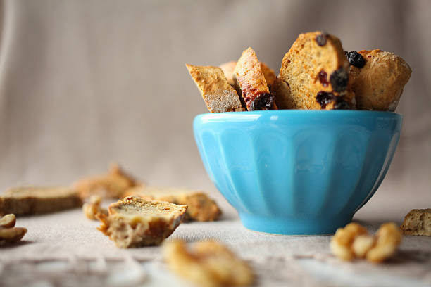 \nItalian biscotti cookies with nuts in the blue bowl on the table with grey linen tablecloth
