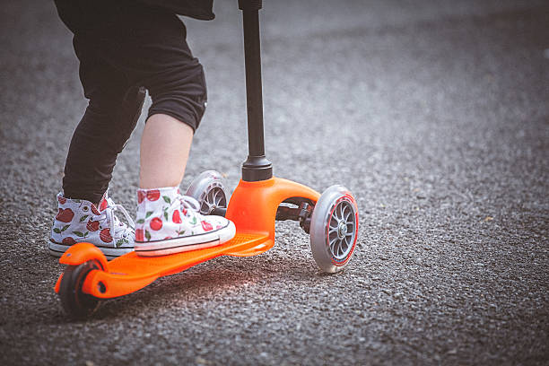 istock Toddler girl riding push scooter on pavement. 586063282