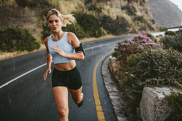 atleta feminina correndo ao ar livre em rodovia - running jogging road exercising - fotografias e filmes do acervo