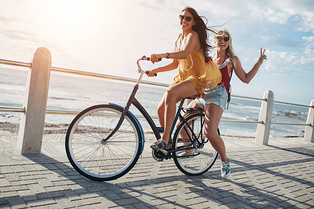 自転車に乗ったスタイリッシュな若い女性の友人 - smart casual outdoors friendship happiness ストックフォトと画像