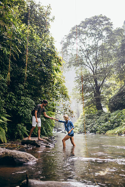 istock Man helping woman crossing stream 586072454