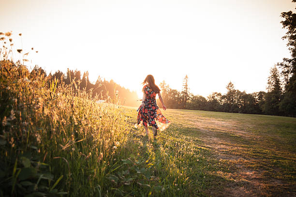 istock Woman walking through meadow at sunset 586074672