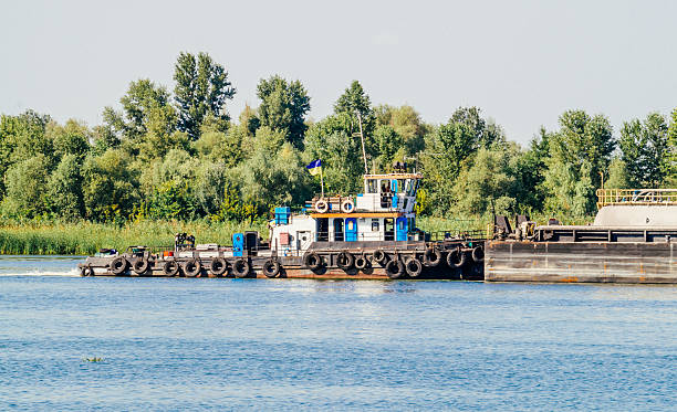 Old-fashioned ship-a tug tows a large barge to the port. Navigation on the river in Europe