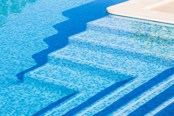 swimming pool steps Swimming pool steps in the morning sunlight with shadows accentuating their pleasant curved shapes. The steps are tiles with tiles of various shades of blue. shades of blue stock pictures, royalty-free photos & images