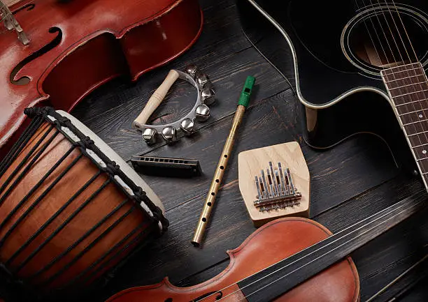 Set of musical instruments on dark wooden background: guitar, violin, harmonica, cello and others. Top view