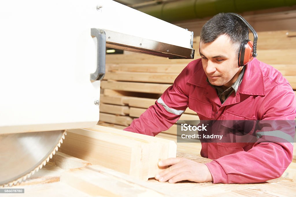 carpentry worker cutting wood cross beam process of carpenter worker with circular saw machine at wood beam cross cutting during furniture manufacture Adult Stock Photo