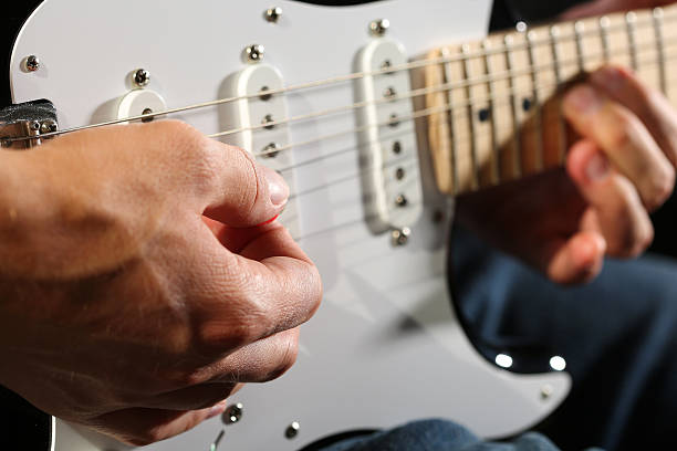 istock Male hands playing electric guitar with plectrum closeup 586082772