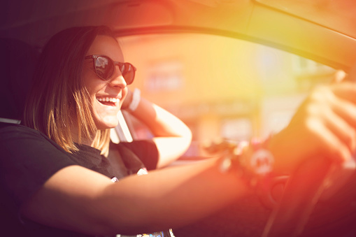 Smiling young woman driving a car.