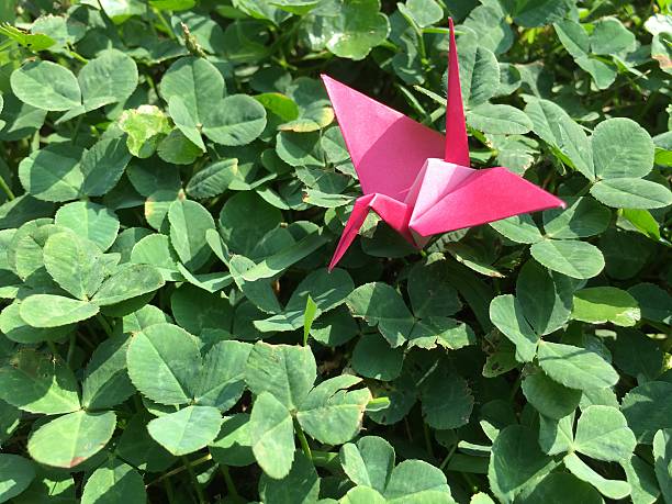 istock Paper crane sitting on green field 586089480