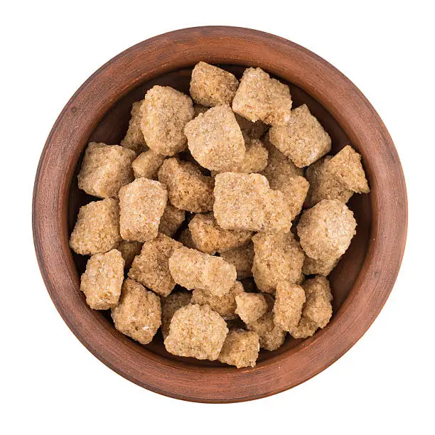 Cubes of whole cane sugar in bowl, isolated on the white background. Top view.