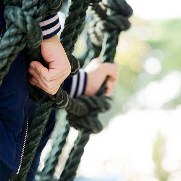 Little asian boy climbing outdoors rope frame.