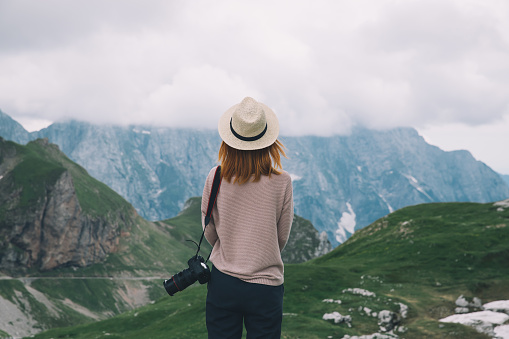 Young woman relaxing outdoor travel freedom lifestyle with mountains on background. Fashionable girl in the Mangart is a mountain in the Julian Alps, located between Italy and Slovenia.