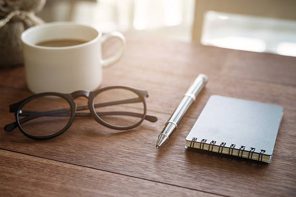 istock Notebook and cup of coffee with sunlight on desk office 586175848