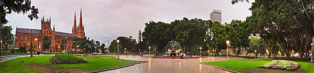 Sy Hyde park rain set pan wide panorama of Sydney Hyde park with Archibald fountain and St Mary cathedral between walk ways, trees and flowers. hyde park sydney stock pictures, royalty-free photos & images