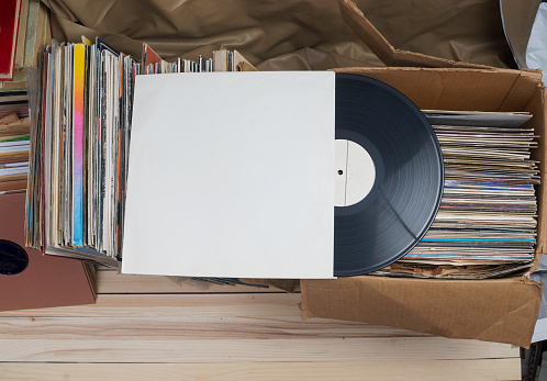 Retro styled image of a collection of old vinyl record lp's with sleeves on a wooden background. Top view.  Copy space.