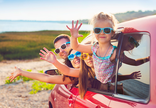 Retrato de una familia sonriente con niños en la playa en coche photo