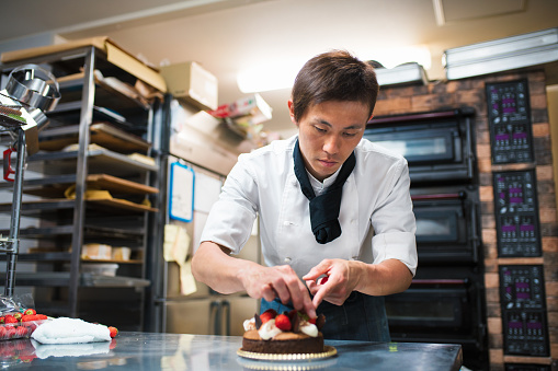 Baker decorating a freshly finished cake. Kyoto, Japan. May 2016
