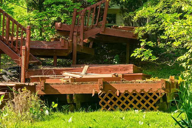 An old, dilapidated backyard deck in the process of being dismantled and removed