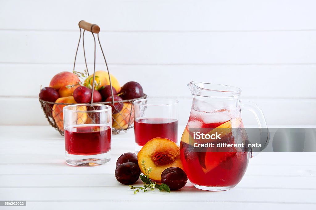 Iced fruit compote with peaches and plums. Cold summer drink. Iced fruit compote with peaches and plums. Cold summer drink with fruit in a basket in the back. Basket Stock Photo