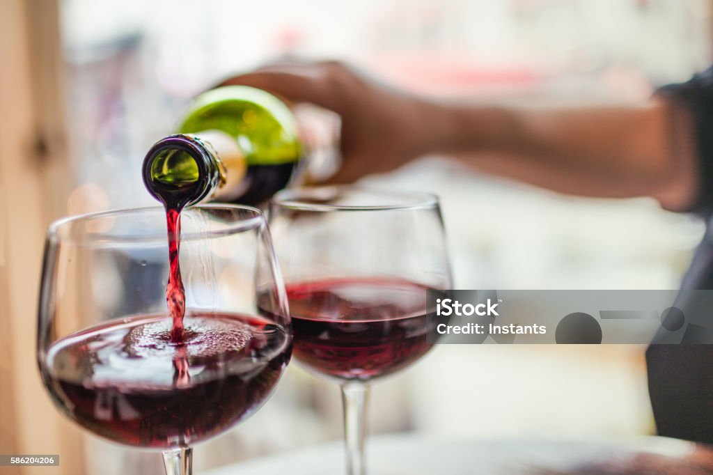 Pouring red wine in glasses Unrecognizable man pouring red wine in two glasses. Red Wine Stock Photo