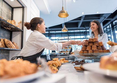 Happy Latin American woman buying pastries at a bakery and smiling - food service concepts
