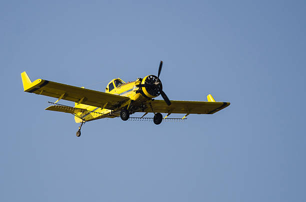 istock Yellow Crop Dusting Plane Flying in a Blue Sky 586209512