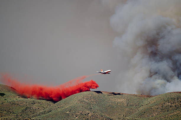 istock White Aircraft Dropping Fire Retardant While Battling Raging Wildfire 586209824
