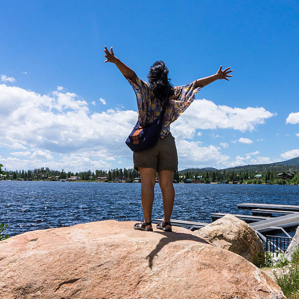woman with arms outstretched in exhilaration for a beautiful summer day on the lake