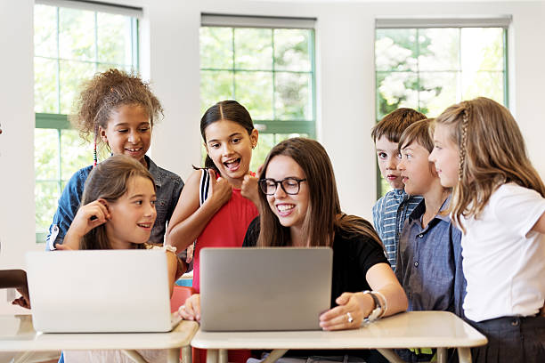 istock School children using laptop with teacher in the classroom 586211354