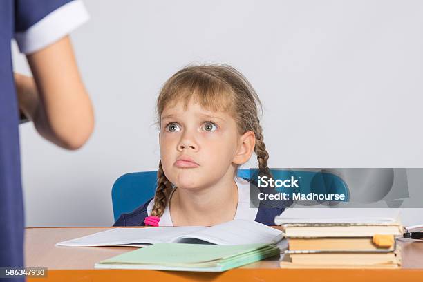 Schoolgirl Sitting At The Desk Angrily Looks At Another Girl Stock Photo - Download Image Now