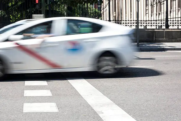 Taxicab crossing Madrid downtown street, Spain. Low motion shot