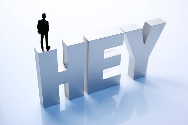 istock Figurine Businessman Standing on Big Letters HEY 586356856
