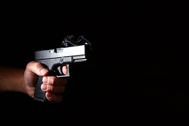 istock Pistol in his hand in the dark 586357330