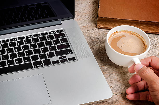 istock Laptop and cup of coffee in hand 586359214