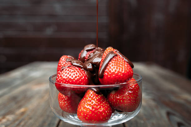 istock Pouring chocolate over strawberry, dark background 586360684