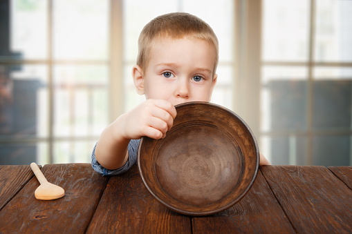 istock Cute blonde boy shows empty plate, hunger concept 586362212