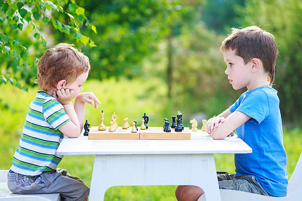 dos niños jugando al ajedrez al aire libre - chess skill concentration intelligence fotografías e imágenes de stock