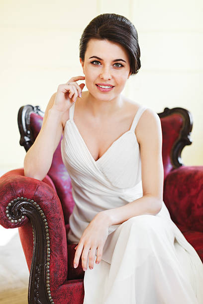 istock Bride in white dress on red armchair 586368358